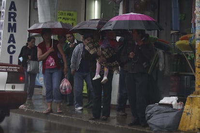 Personas esperan el transporte público bajo la lluvia ocasionada por la tormenta tropical Carlotta en la ciudad de Oaxaca, en junio de 2024. 