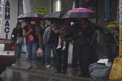 Personas esperan el transporte público bajo la lluvia ocasionada por la tormenta tropical Carlotta en la ciudad de Oaxaca, en junio de 2024.