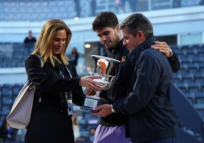 Alcaraz muestra el trofeo a sus padres, Virginia y Carlos.