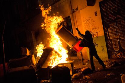 Un manifestante lanza un contenedor de basuras a las llamas durante la protesta.