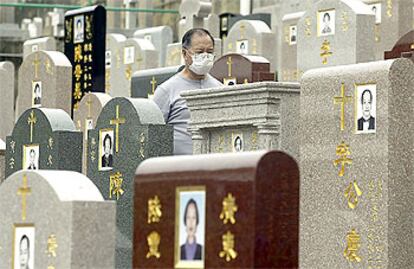 Un hombre, protegido por una mascarilla, pasea por el cementerio cristiano de Hong Kong.