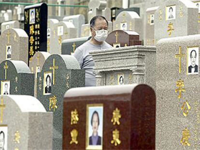 Un hombre, protegido por una mascarilla, pasea por el cementerio cristiano de Hong Kong.