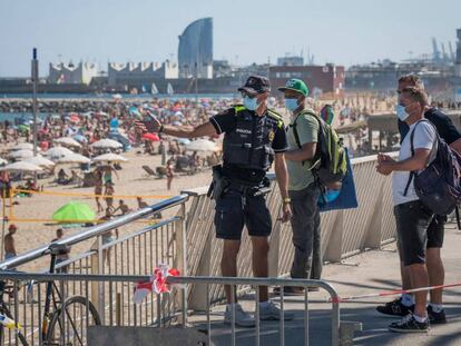 Un policia municipal explica a uns vianants la situació de la platja del Bogatell a Barcelona, diumenge.