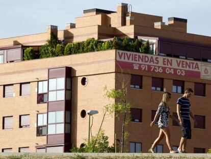 Una pareja pasea por delante de una promoci&oacute;n de viviendas en Madrid. 