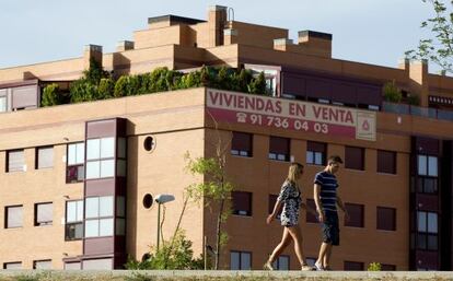 Una pareja pasea por delante de una promoción de viviendas en Madrid.