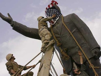 Soldados de EE UU cubren con la bandera de su país la cara de la estatua de Sadam Husein, antes de derribarla el 9 de abril de 2003.