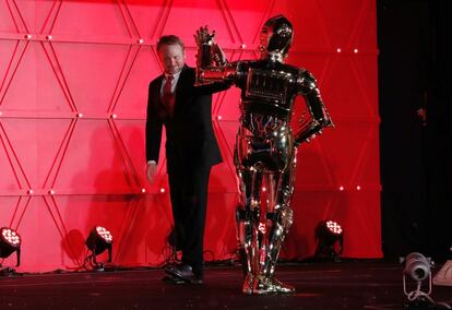 El director de la película Rian Johnson (izquierda) saluda al personaje de ficción C-3PO.