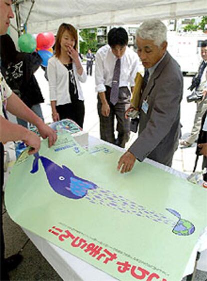 La Asociación Ballenera de Japón enseña sus carteles con el lema <i>No podemos tolerarlo</i>, junto a una ballena que devora todos los peces del planeta.
