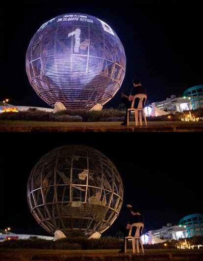 Un hombre sentado frente a un globo terráqueo antes y después de la Hora del Planeta, en Manila (Filipinas).