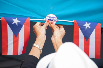 Una voluntaria de la campaña republicana cuelga banderas puertorriqueñas fuera de la oficina de Latinos por Trump en Reading 