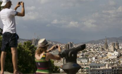 Dos turistas toman fotos de Barcelona desde Montjuic.