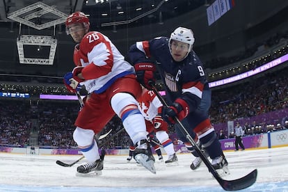 El ruso Vyacheslav Voynov (izquierda) pugna con el estadounidense Zach Parise (derecha) durante el partido de hockey entre EEUU y Rusia de la ronda preliminar del grupo A en los Juegos de Sochi.