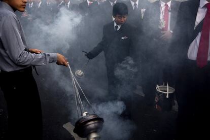 Varios niños zarandean el incienso que purifica el camino de la procesión del martes santo conocida como "La Reseña", en el centro de la ciudad de Guatemala, el 16 de abril de 2019.