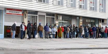 Varias personas hacen cola ante una oficina de empleo. 