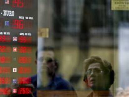 Varios viandantes observan una pantalla con los valores del cambio internacional de divisa en Estambul, Turquía. EFE/Archivo