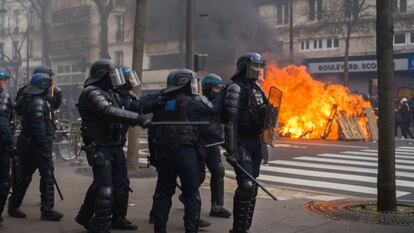 Policías antidisturbios cargan junto a una barricada que arde en la masiva manifestación, el jueves.