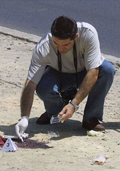 Un policía recoge pruebas, ayer,  en el lugar del crimen.