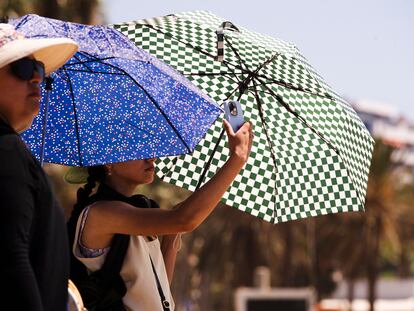 Unos turistas se protegen del sol en la playa de la Malagueta donde las temperaturas llegan hasta los 34º en Málaga.