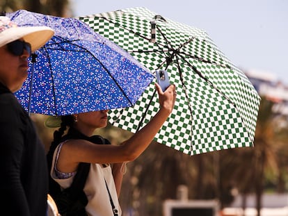 Unos turistas se protegen del sol en la playa de la Malagueta donde las temperaturas llegan hasta los 34º en Málaga.