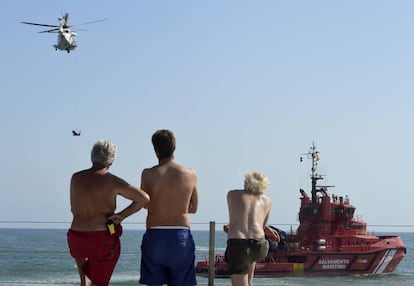 Varios bañistas observan en Valencia unas prácticas de salvamento marítimo.