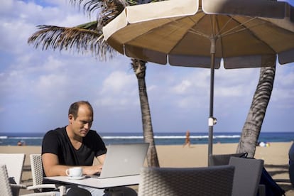 Un nómada digital trabaja con su portátil en la Playa de Las Canteras, en Las Palmas de Gran Canaria.