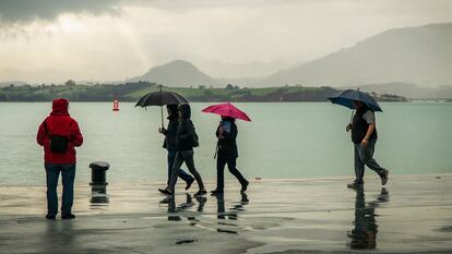 Un grupo de gente paseaba bajo la lluvia junto a la bahía de Santander, este viernes.