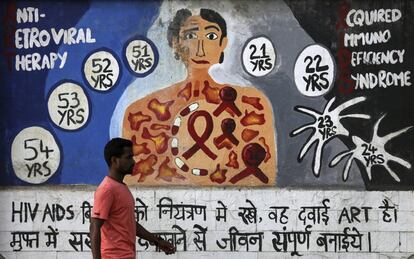 Un hombre camina junto a un mural decorado con motivos que hacen referencia al virus del sida durante el Día Mundial de esta enfermedad en Bombay, India.