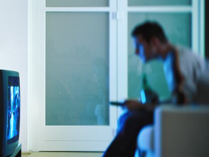 Un hombre, sentado frente al televisor en el salón de su casa.