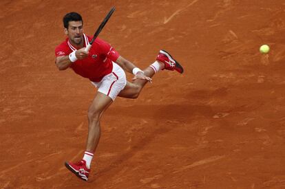 Novak Djokovic se tiene que emplear a fondo para devolver una bola a Nadal.