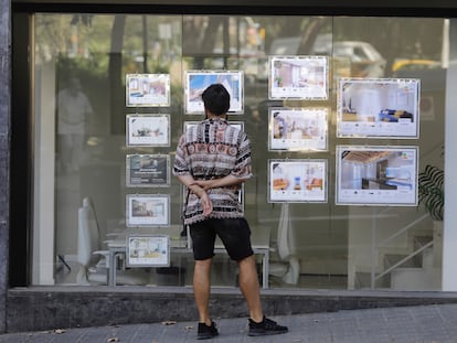 Un joven mira anuncios de alquiler de una inmobiliaria en Barcelona.