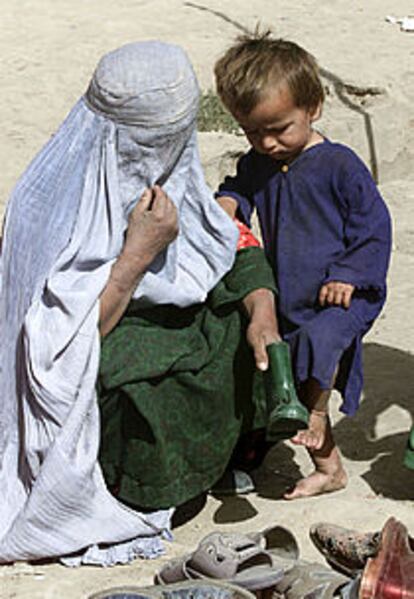 Una mujer comprando zapatos para su hijo en el mercado de Joja Bahawuddin, en Afganistán.
