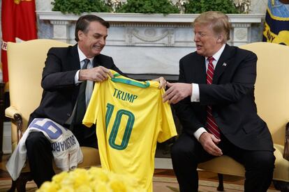 El presidente brasileño, Jair Bolsonaro, entrega a su homólogo estadounidense Donald Trump, una camiseta de fútbol de la selección nacional brasileña con su nombre, en el Despacho Oval de la Casa Blanca.