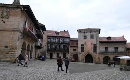 Visitantes pasean por la plaza Mayor de Santillana del Mar, con el Ayuntamiento a la izquierda y la Torre de Don Borja al frente.