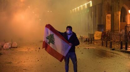 Un manifestante posa con una bandera de Líbano este sábado en medio de una nube de gases lacrimóngenos cerca del Parlamento libanés en Beirut.  