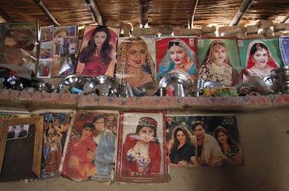 Interior de la vivienda de un recolector de algodón, donde se ven utensilios colocados en un estante en una pared de barro adornada con carteles de estrellas de Bollywood.