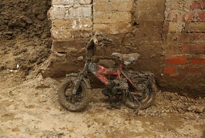 Una bicicleta infantil en un edificio cubierto de barro, en Carapongo Huachipa, Lima.