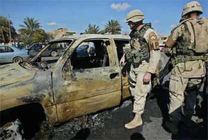 Dos soldados de EE UU, ante los restos de un vehículo calcinado durante un ataque, ayer en Bagdad.