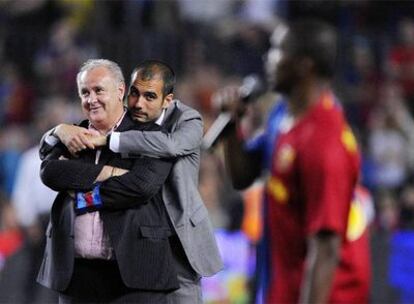 Pep Guardiola abraza al delegado del Barça, Carlos Naval, mientras Eto&#39;0 se dirige al público en la celebración del sábado en el Camp Nou por los títulos de Liga y Copa.