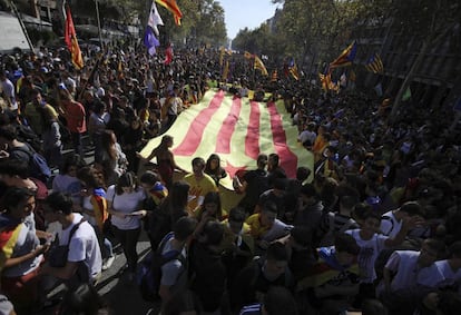 Varios jóvenes sostienen una enorme bandera independentista catalana durante la huelga de estudiantes en Barcelona.