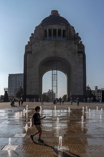 Transeúntes juegan en las fuentes del Monumento a la Revolución.