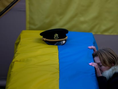 FILE - Svitlana Havryliuk kneels next to the coffin of her husband, Serhii, 48, at his funeral in Tarasivka village, near Kyiv, Ukraine, on Feb. 15, 2023. Havryliuk, an officer of the Azov Assault Brigade, died while defending the Azovstal steel plant in Mariupol on April 12, 2022. He was finally buried after DNA tests confirmed his identity. (AP Photo/Emilio Morenatti, File)