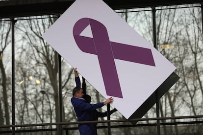 Un operario coloca un lazo contra la violencia de género en el Ministerio de Sanidad.