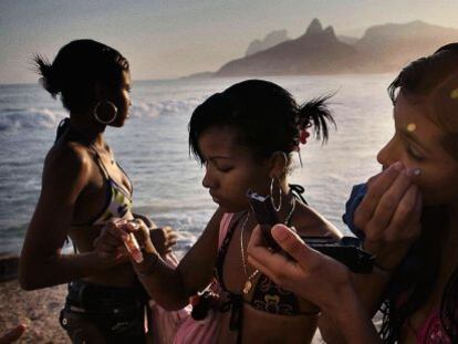 Unas adolescentes se maquillan en la playa de Copacabana.