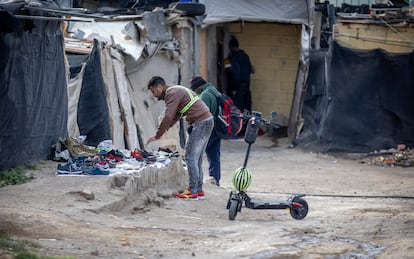 Dos migrantes buscan calzado en el asentamiento de Atochares, en la localidad de San Isidro, dentro del municipio de Níjar, Almería.