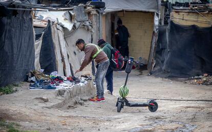 Dos migrantes buscan calzado en el asentamiento de Atochares, en la localidad de San Isidro, dentro del municipio de Níjar, Almería.