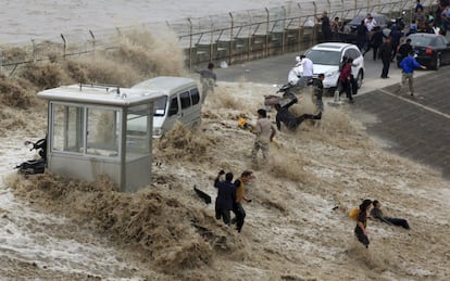 Un grupo de viandantes es arrastrado por la marejada de una ola en las orilla del río Qiantang, en Hangzhou (China).