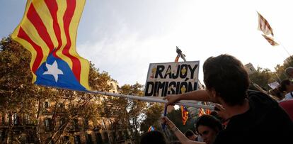 Un hombre sostiene una estelada junto a una pancarta de "Rajoy dimisión" durante la huelga general en Barcelona.