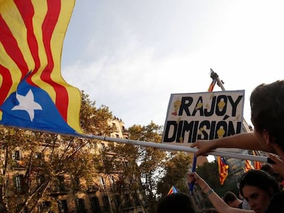 Un hombre sostiene una estelada junto a una pancarta de &quot;Rajoy dimisi&oacute;n&quot; durante la huelga general en Barcelona. 