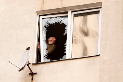 Un hombre inspecciona los daños junto a una ventana destrozada en el lugar de un ataque ruso, en medio del ataque de Rusia a Ucrania, en Kiev.