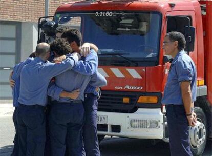 Compañeros de uno de los bomberos fallecidos, Ramón Espinet, se abrazan desconsolados tras su funeral.